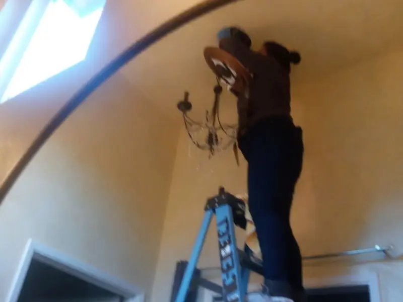 Electrician installing a chandelier in a Binghamton residence